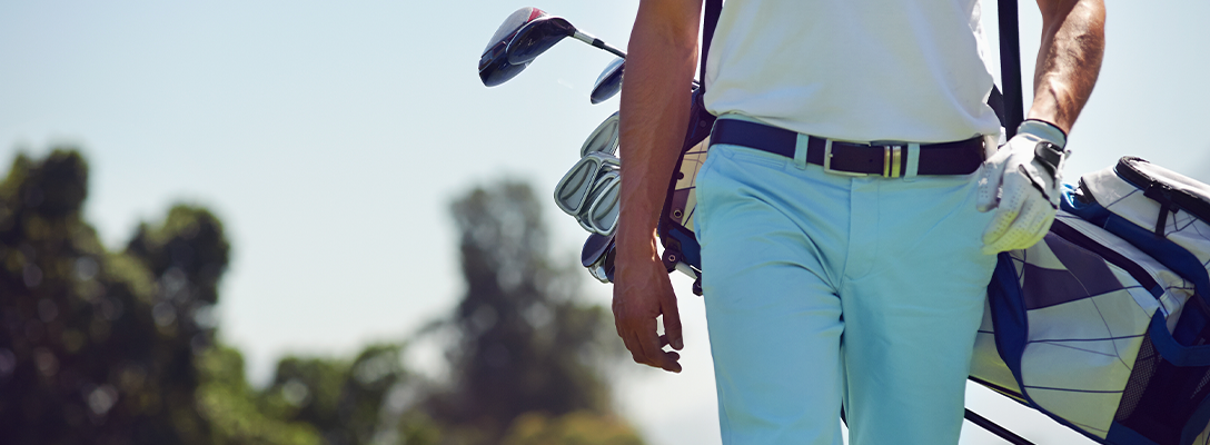 Man Walking with Golf Clubs During Golf Tournament