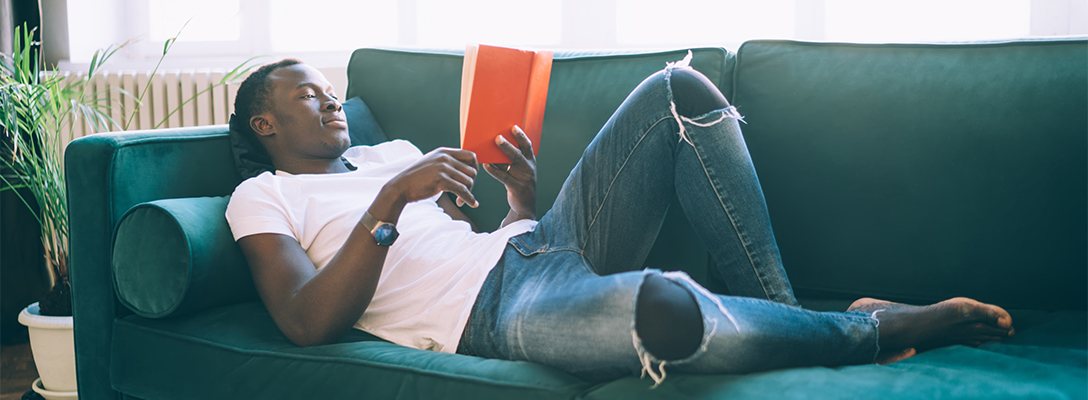Man on Couch Reading Book About Basketball