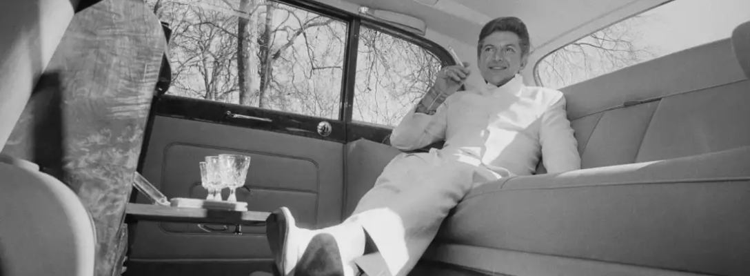 Liberace in Back of Rolls Royce with Champagne Glasses