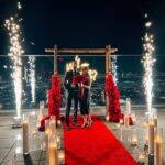 outdoor wedding proposal las vegas strip view rooftop balcony with sparkler fountain and neon will you marry me sign and red carpet candles and flowers